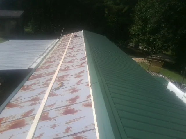 Old rusted panels beside newly installed green metal roofing — Wind Damage Roof Repair by Roofing Brothers in Athens